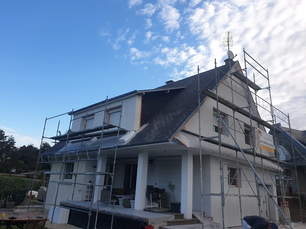 Chantier d'isolation thermique par l'extérieur sur une maison à étage avec échafaudage dans le Calvados