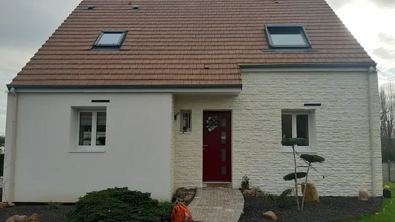 Maison à toit de tuiles avec soubassement en pierre et enduit clair après travaux dans le Calvados